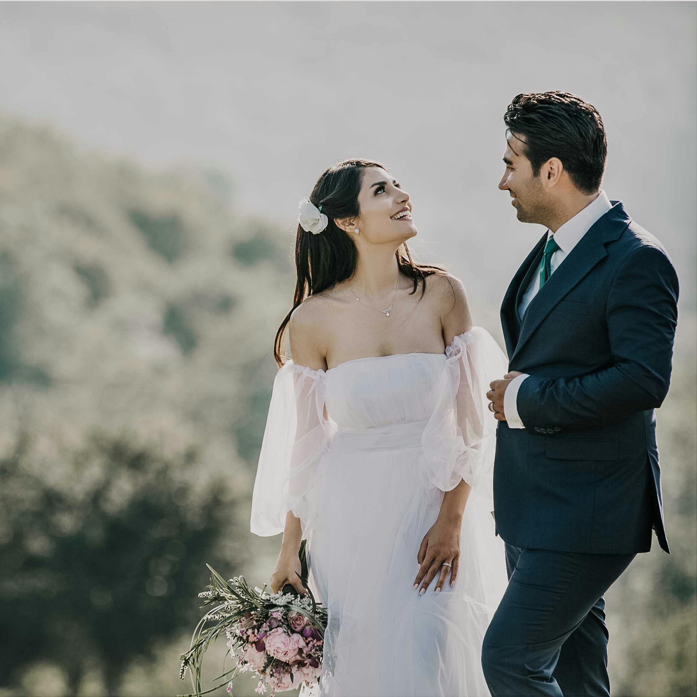 A joyful bride and groom share a loving glance in a beautiful outdoor setting.