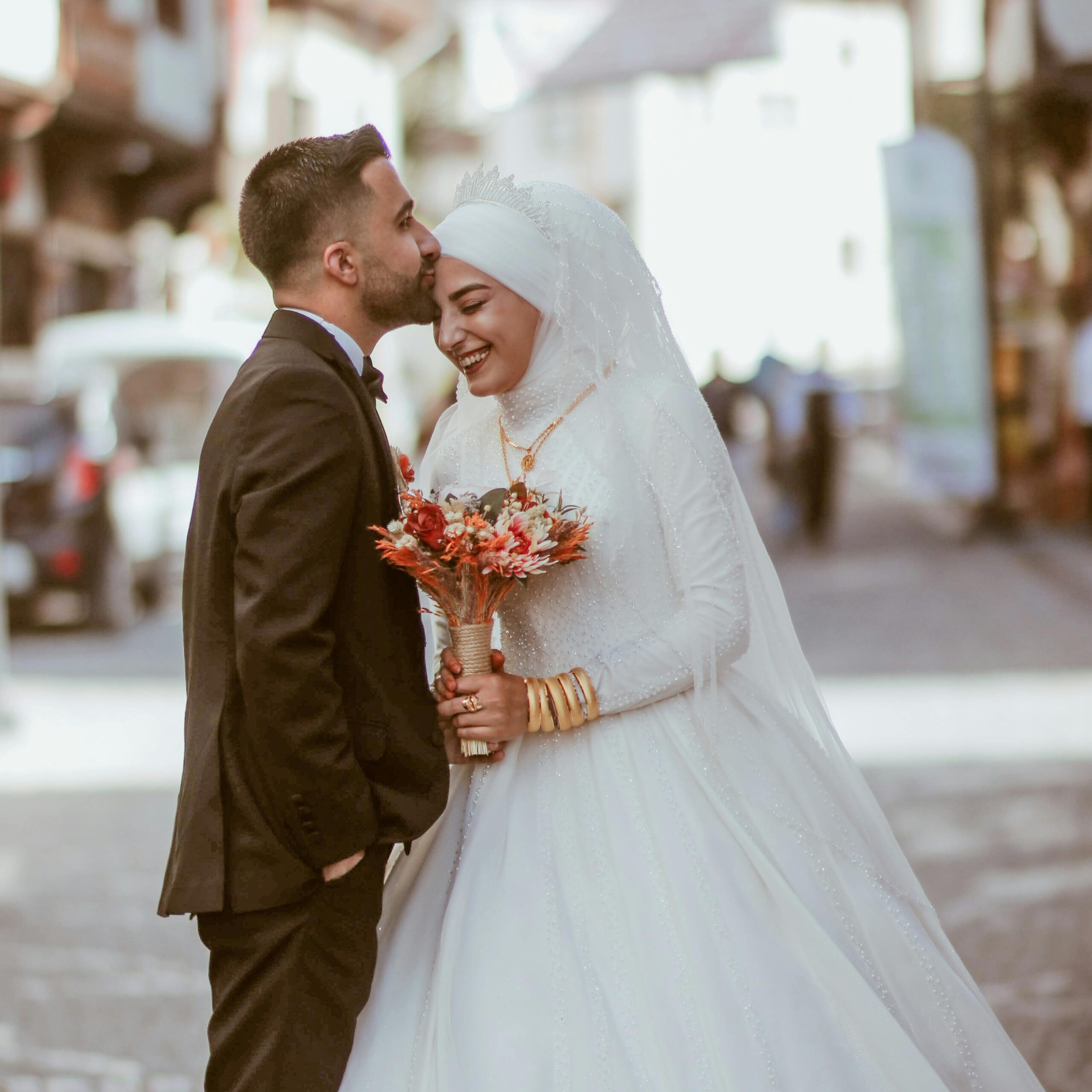 Smiling newlyweds embrace in a joyous street wedding moment, capturing romance and tradition.